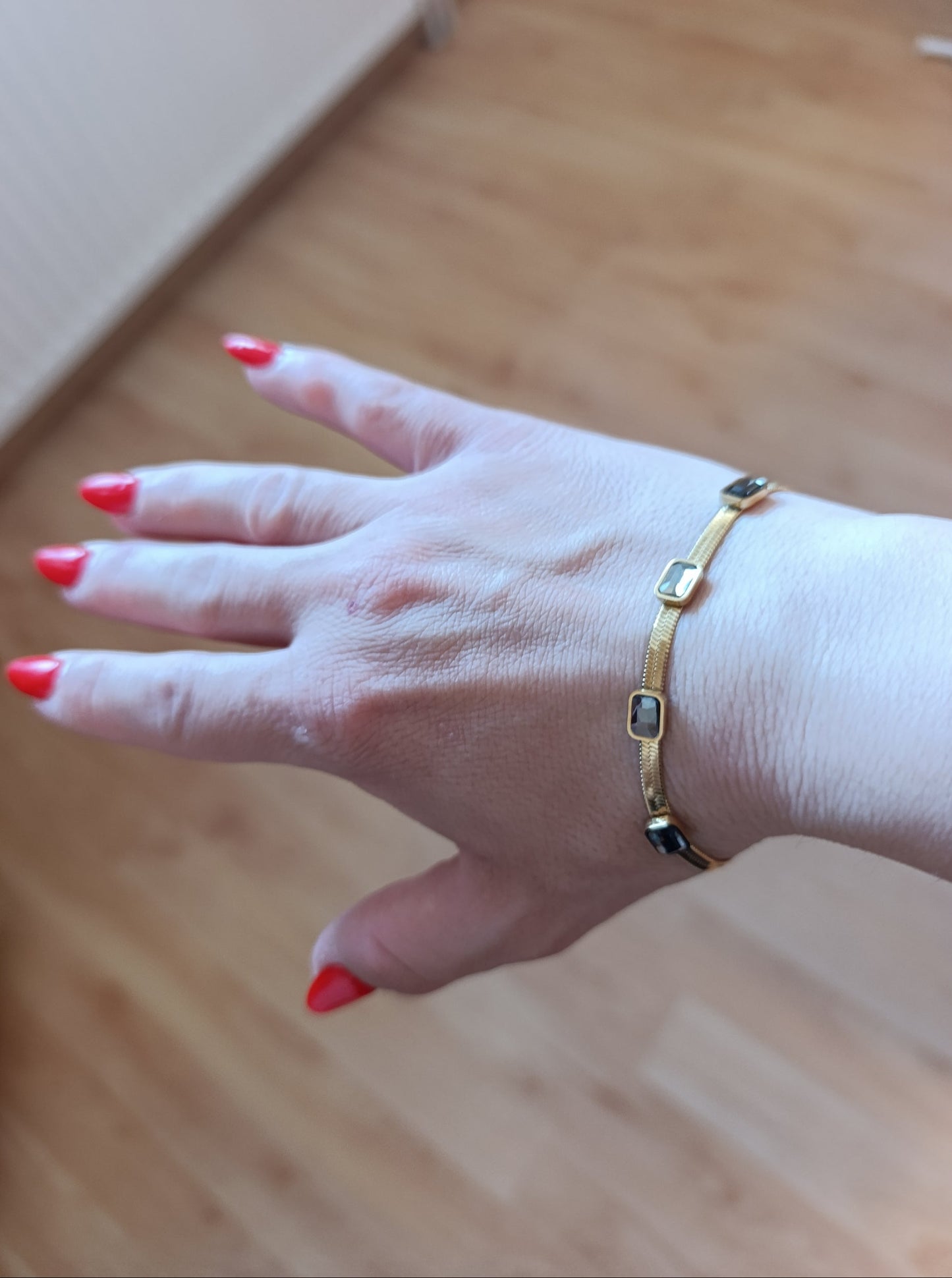 Χρυσό snake βραχιόλι stainless steel φορεμένο στον καρπό με μαύρες ορθογώνιες πέτρες και λεπτή επίπεδη αλυσίδα.