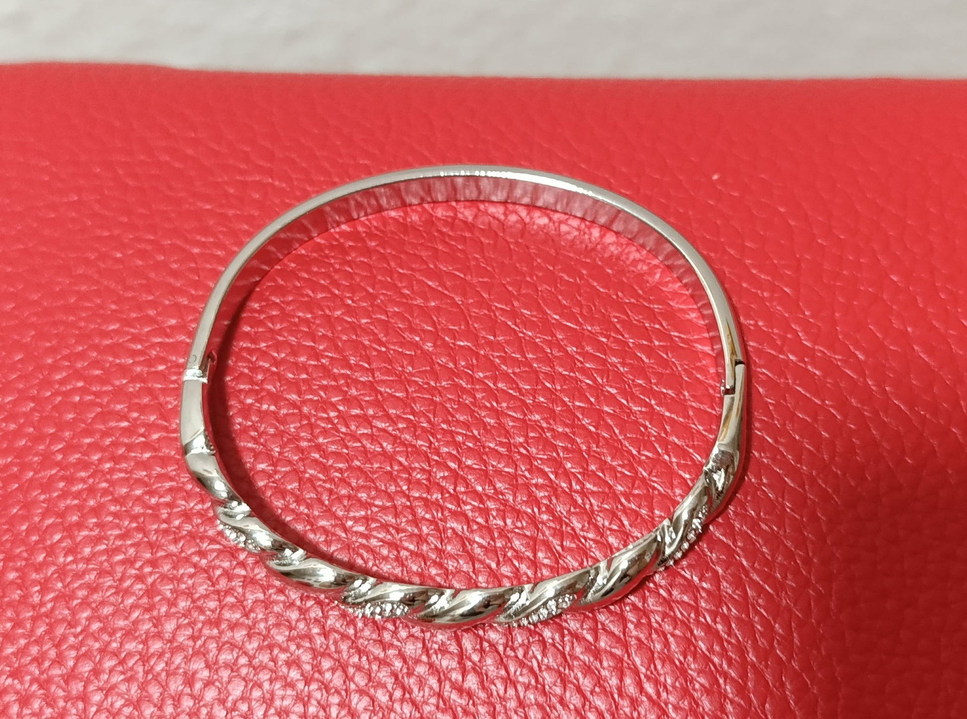 Ασημί χειροπέδα stainless steel με κυκλικό σχήμα, διάμετρο 6 εκ. και μπροστινό στριφτό σχέδιο με ζιργκόν.